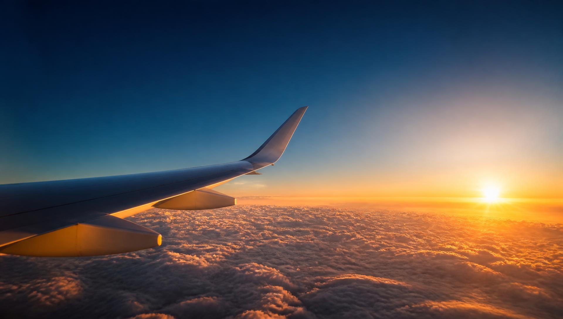 View of an airplane wing above the clouds at sunset